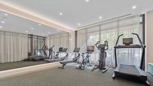 Une salle de sport moderne équipée d’appareils de cardio, de miroirs et de grandes fenêtres.