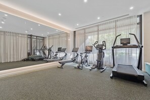Academia moderna com máquinas de cardio, espelhos e grandes janelas.