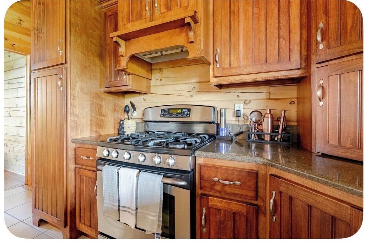 A kitchen with wooden cabinets, a stainless steel stove, and a countertop.