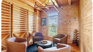Un intérieur en bois comprenant un espace salon, un luminaire au plafond et une fenêtre avec des stores.