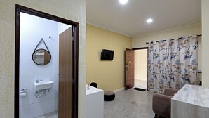 Ein Zimmer mit Bad, Schreibtisch, Stuhl, Fernseher und Vorhang.