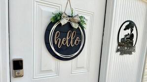 A white door with a 'hello' sign, a small metal bell, and a keypad lock. - Romantic King Bed, Heart Shaped Hot Tub, Fire Pit (Zaleski)
