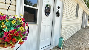A house with a white door, a window, and a hanging flower basket. - Romantic King Bed, Heart Shaped Hot Tub, Fire Pit (Zaleski)