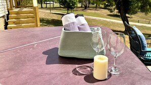 A table with a candle, two glasses, and a basket with folded towels. - Romantic King Bed, Heart Shaped Hot Tub, Fire Pit (Zaleski)