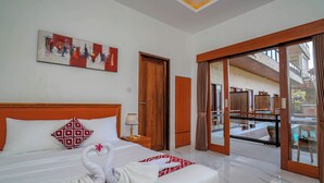 Une chambre d’hôtel avec un lit, une tête de lit en bois, un tableau, une porte en bois et une vue sur un espace extérieur avec une piscine.