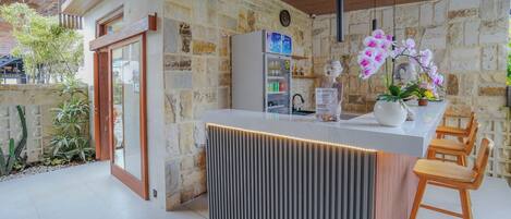 Eine moderne Küche mit einem eingebauten Kühlschrank, Holzbarhocker und einer Orchideenpflanze im Topf.