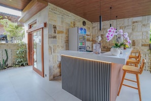 Una cocina moderna con refrigerador empotrado, taburetes de bar de madera y una orquídea en maceta.