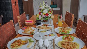 Une table à manger avec différents plats, un vase de fleurs et une boisson.