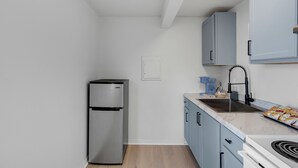 A kitchen with a stainless steel refrigerator, a sink, and light blue cabinets. - Coastal Cottage STEPS to BEACH and downtown Old Orchard Beach - Prime Location (Old Orchard Beach)
