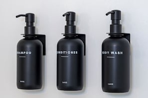 Drei schwarze Flaschen mit Shampoos, Conditioner und Duschgel, jeweils mit Pumpaufsatz und der Aufschrift 160 Unzen.