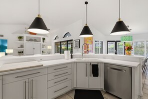 A modern kitchen with white cabinetry, stainless steel appliances, and pendant lighting. - Beachside Bliss in Marco Island (Marco Island)