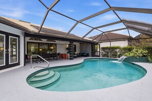 A swimming pool with a glass enclosure, steps leading into the pool, and outdoor seating. - Beachside Bliss in Marco Island (Marco Island)