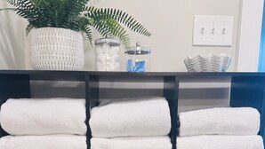 A neatly organized shelf with folded white towels, a black hairdryer, and a blue first aid kit.