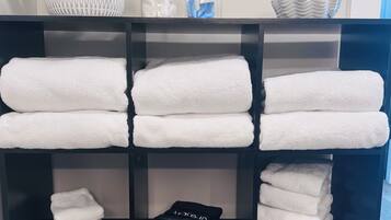 A neatly organized shelf with folded white towels, a black hairdryer, and a blue first aid kit.