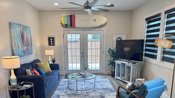 A living room with a blue sofa, a coffee table, a TV, and a ceiling fan.