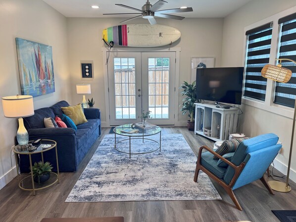 A living room with a blue sofa, a coffee table, a TV, and a ceiling fan.