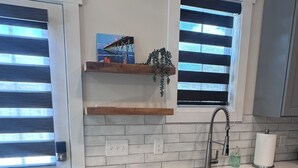 A kitchen with a built-in dishwasher, a sink, and a window with blinds.