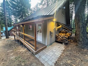 A cabin with a wooden deck, a door, and a stack of firewood. - Our Family Cabin!  Getaway from town - Gateway to adventure - Space to reconnect (Cle Elum)