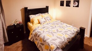 Un dormitorio con cama, mesitas de noche y decoración en la pared.
