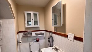 Un baño con inodoro, lavabo, espejo y armarios.