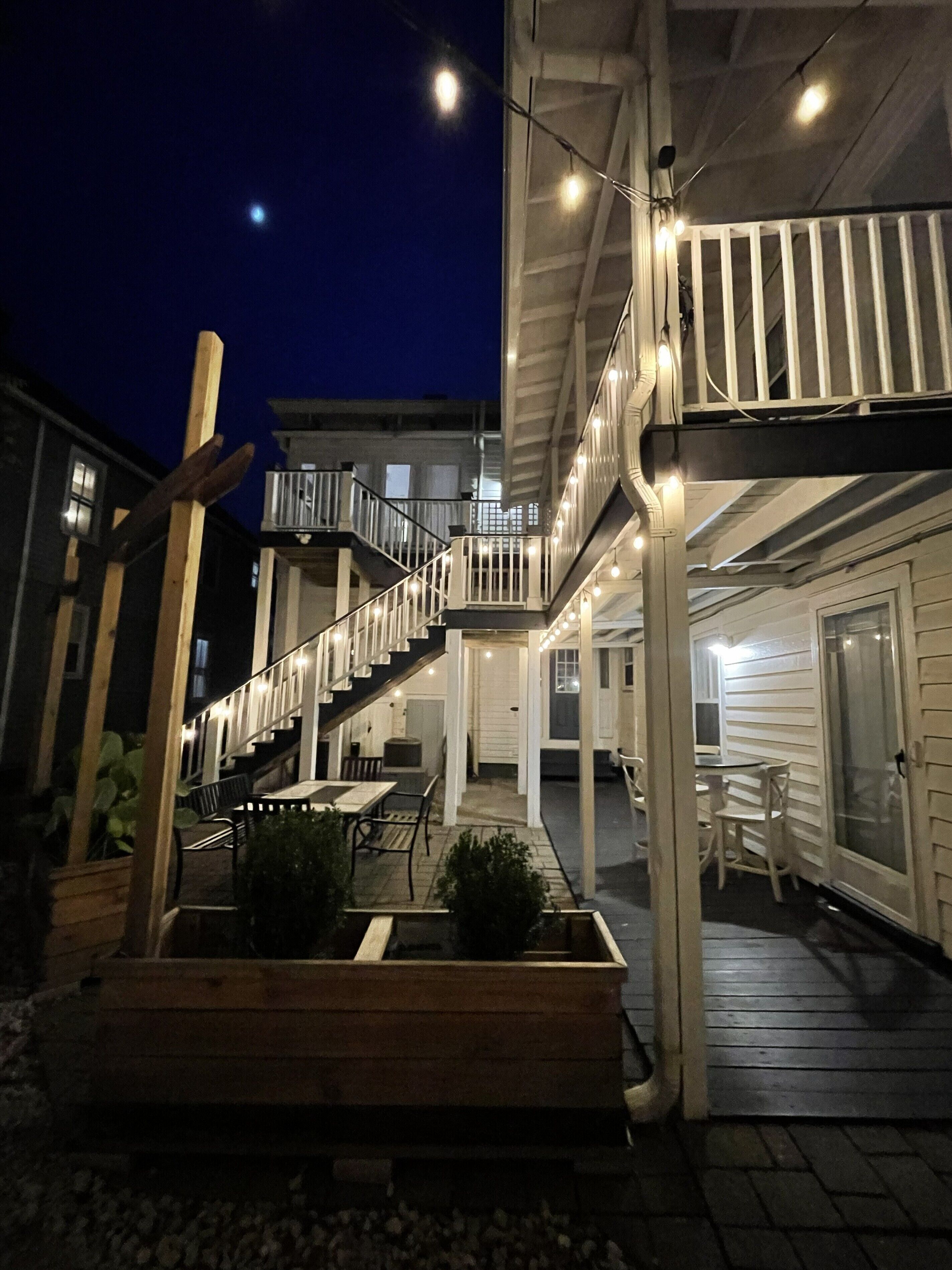 A covered outdoor area with a wooden staircase, seating, and planters.