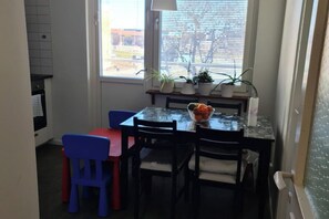 Un coin repas avec une table, des chaises et un saladier rempli de fruits.