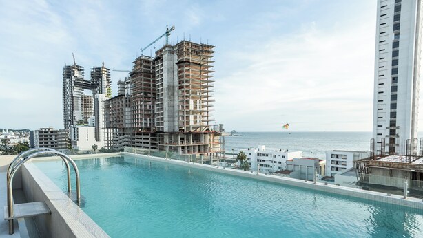Ein Pool mit Blick auf das Meer und einem Baustelle im Hintergrund.