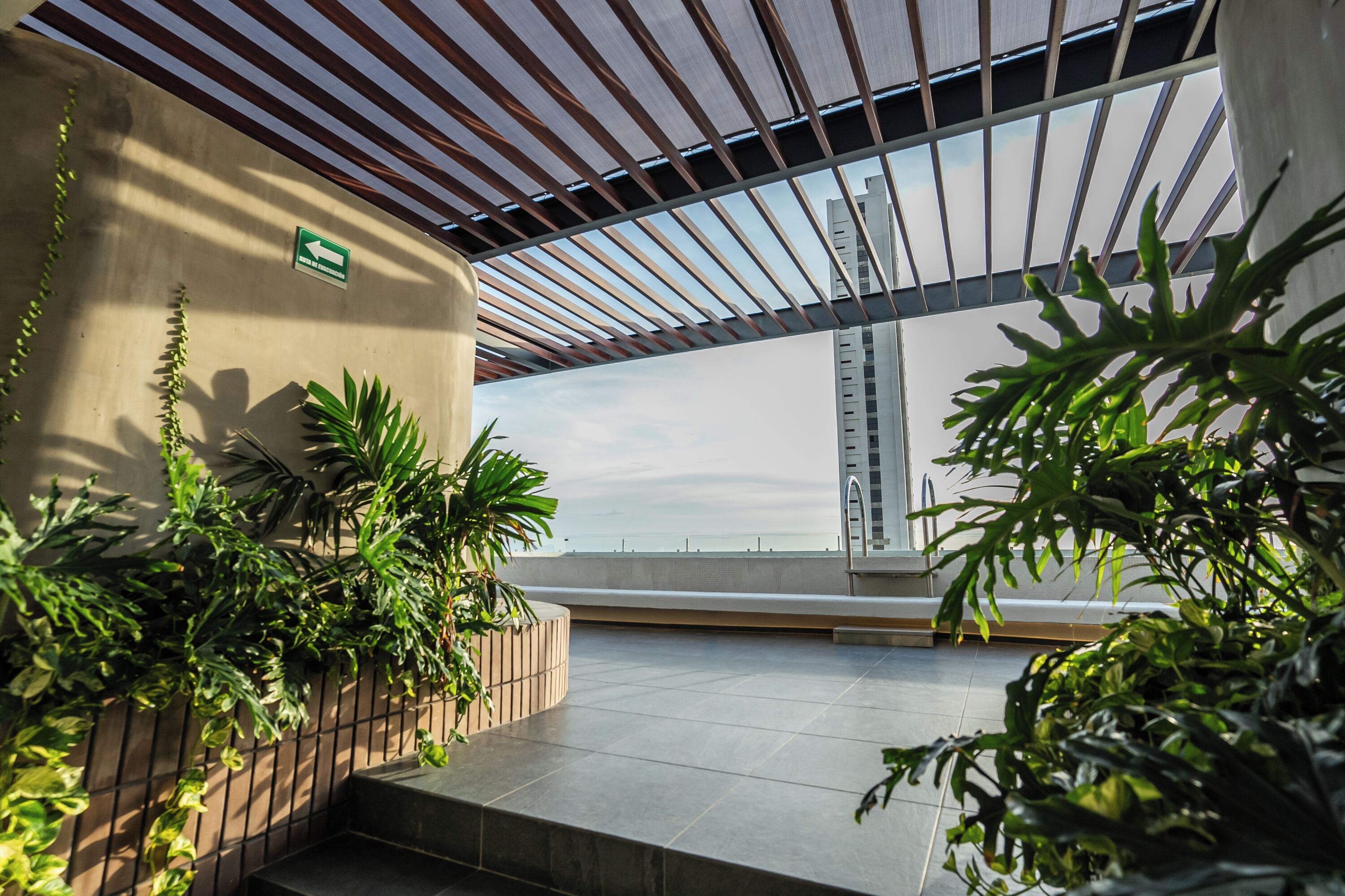 An indoor area with a view of a building, a directional sign, and potted plants.