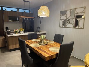 A modern kitchen with a wooden dining table, black chairs, and a decorative wall piece. - Cozy retreat in Mazatlan | Close to beach, restaurants and boardwalk (Mazatlán)