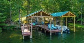 A wooden dock with a covered seating area and a boat. - Four bedrooms in two side-by-side rustic lake cabins in Spring City, TN (Spring City)