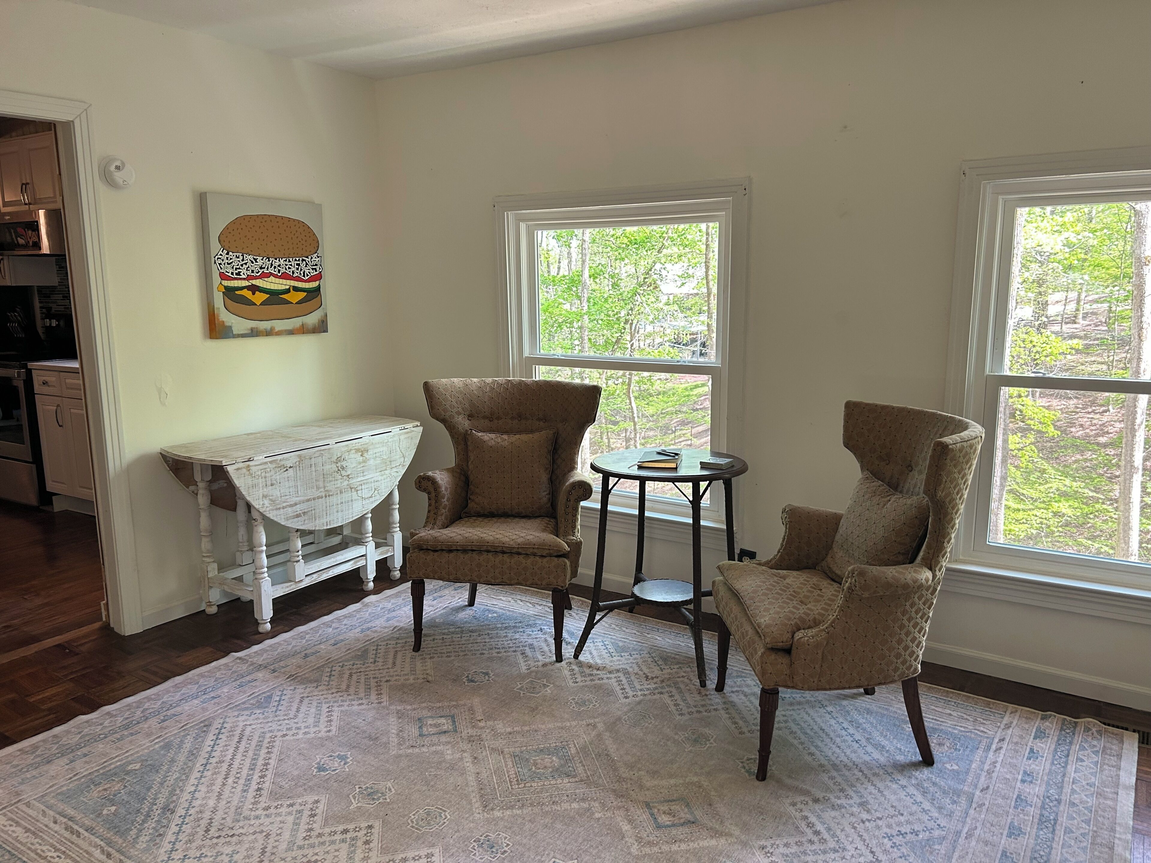 A room with a dining table, two armchairs, a small round table, and a rug.