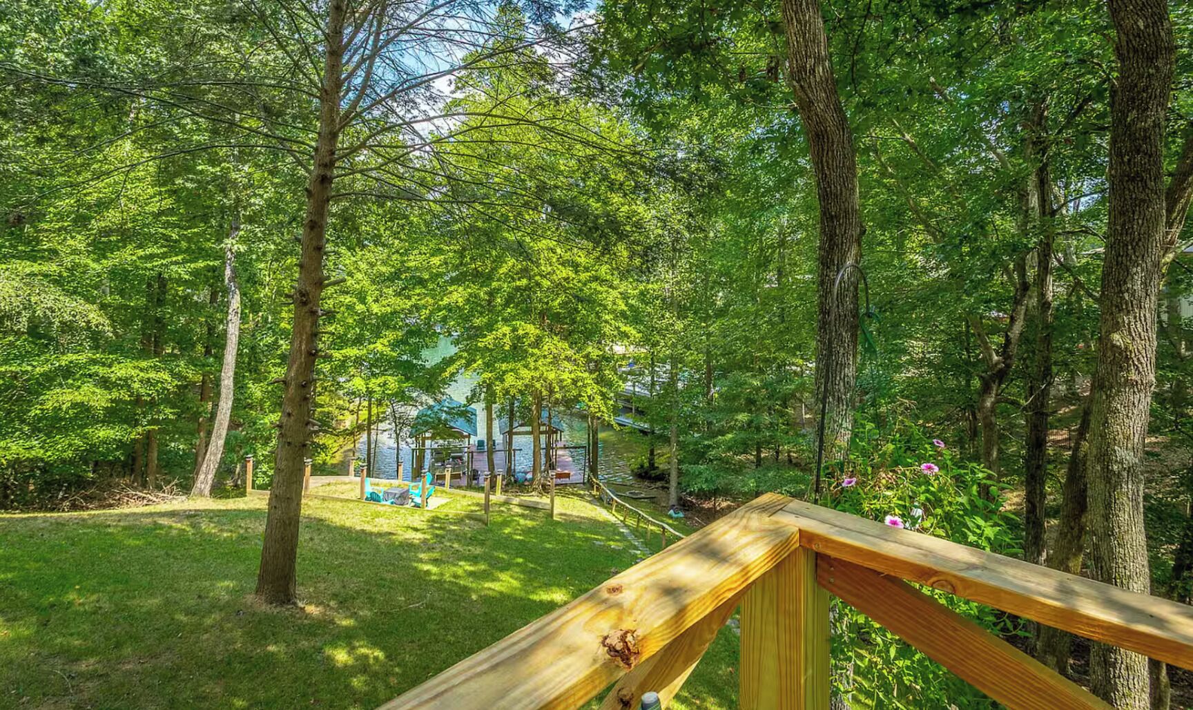 A wooden deck overlooking a lush green forest with a gazebo and outdoor seating area.