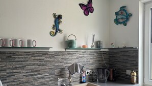 Une cuisine moderne avec un dosseret en granit, un évier en acier inoxydable et des œuvres d’art décoratives au mur.