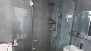 Un baño con ducha de vidrio, lavabo blanco y piso de baldosas.