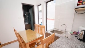 Una cocina compacta con una mesa de madera, sillas, encimera de granito, un lavabo y una ventana.