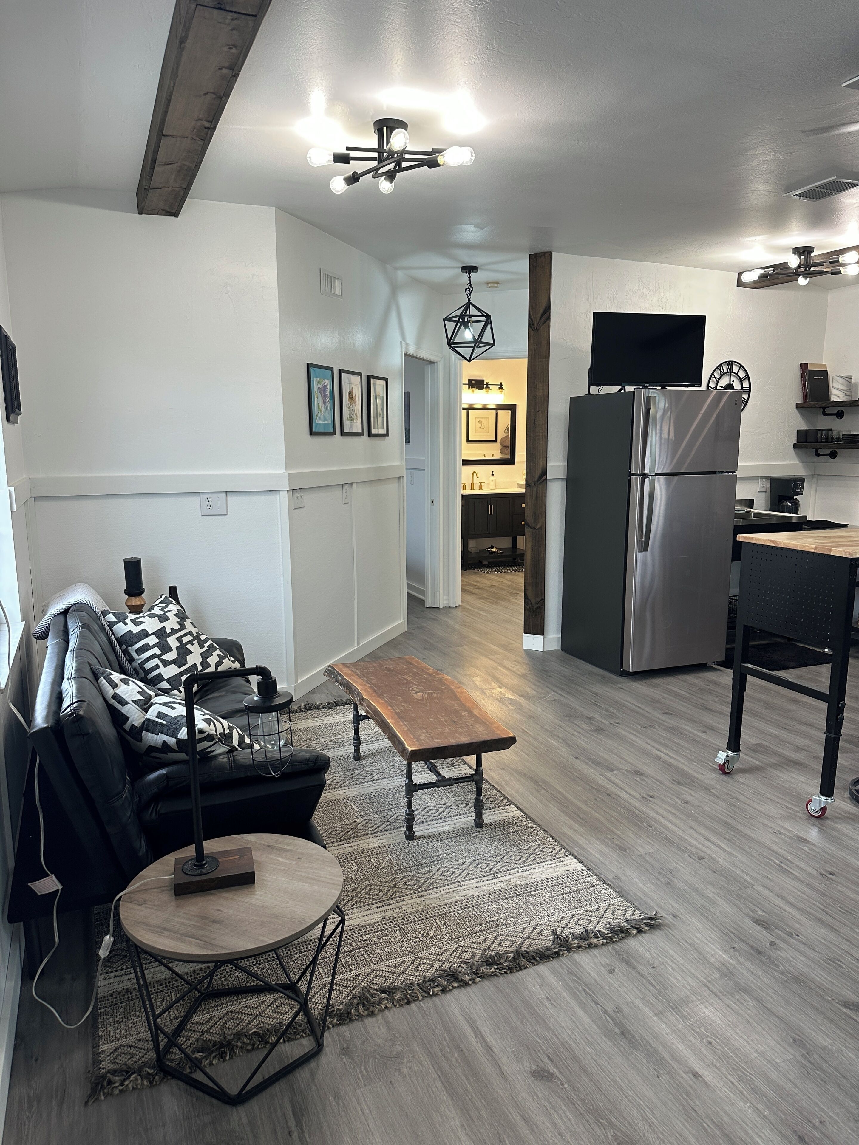 A modern kitchen with a refrigerator, a dining table, and a seating area with a sofa and a coffee table.