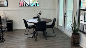 Un coin repas comprenant une table ronde, quatre chaises, un ventilateur de plafond et une grande fenêtre donnant sur un beau paysage.