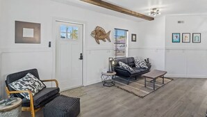 Un salon avec un canapé, une table basse, un fauteuil, un tapis et une porte.