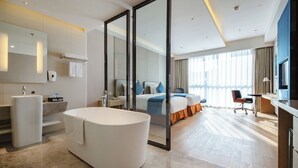 A modern hotel room with a large bathtub, a separate shower area, a bed with a view, and a desk with a chair. - H Crytal Hotel (Jinma Road, Dalian Development Zone) (Dalian)