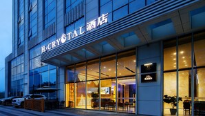A hotel exterior with large glass windows, a sign reading 'H CRYSTAL HOTEL,' and a few parked cars. - H Crytal Hotel (Jinma Road, Dalian Development Zone) (Dalian)