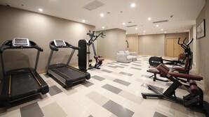 A gym with treadmills, weight machines, and a white couch. - H Crytal Hotel (Jinma Road, Dalian Development Zone) (Dalian)