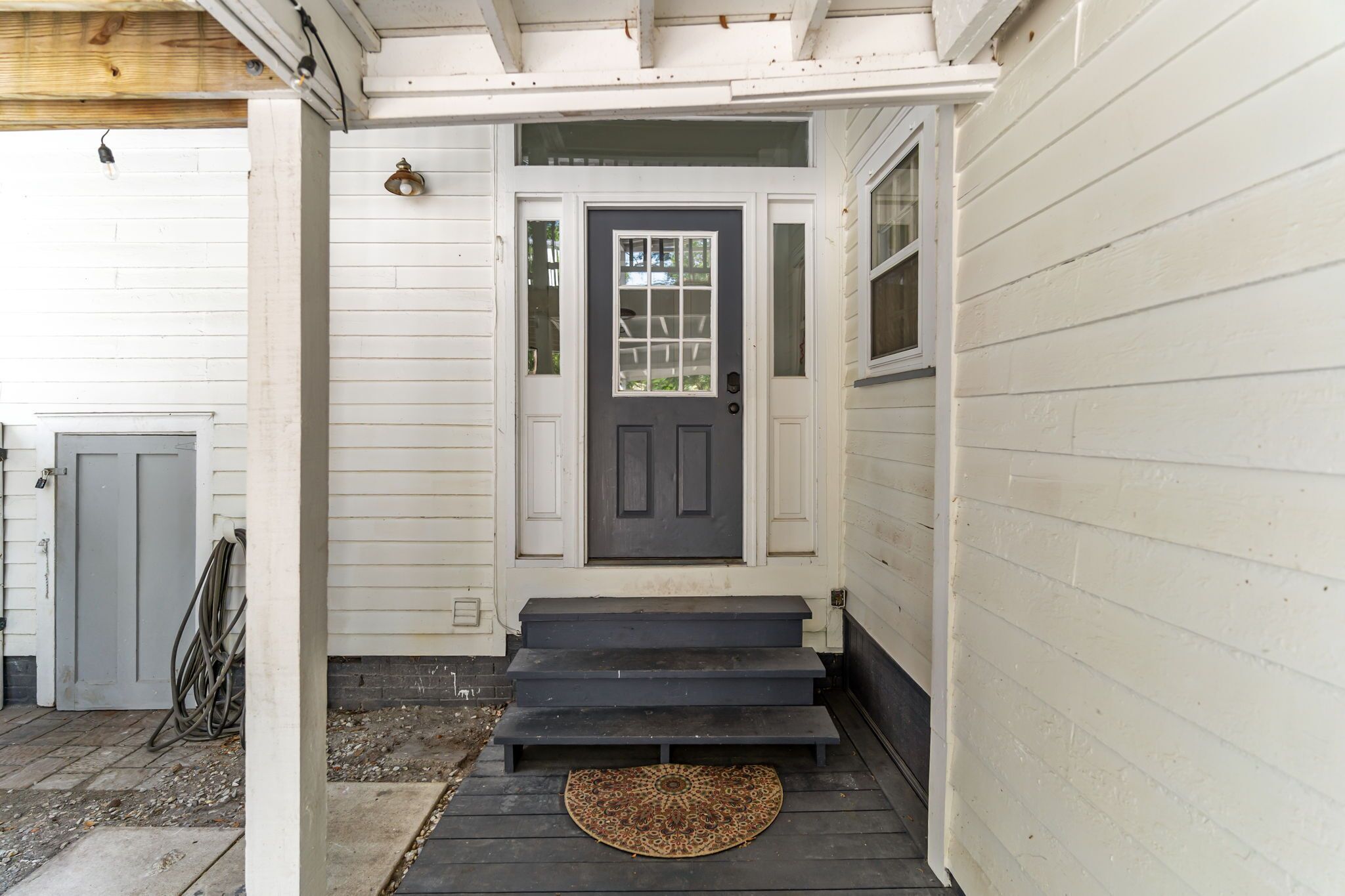 A white house with a dark front door, steps leading to the entrance, and a doormat on the steps.