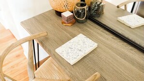 Ein Holztisch mit gewobenen Stühlen, einer gewobenen Lampe und einer kleinen Dekobox.
