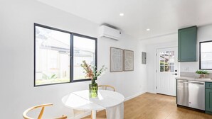 Une cuisine moderne équipée d’un lave-vaisselle, un coin repas avec une table ronde et des chaises, et une grande fenêtre donnant sur l’extérieur.