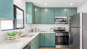 Une cuisine moderne avec des armoires de couleur turquoise, des appareils électroménagers en acier inoxydable et un plancher en bois.