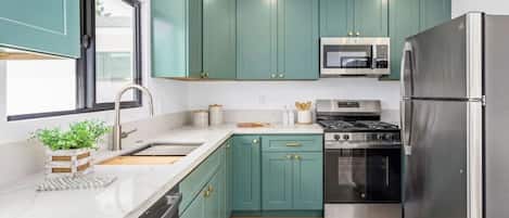 Una cocina moderna con armarios color turquesa, electrodomésticos de acero inoxidable y suelo de madera.