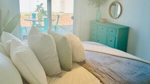 A bedroom with a bed, a teal dresser, and a view of the outdoors. - The Orkney - A Modern Coastal Cardiff Residence (Encinitas)