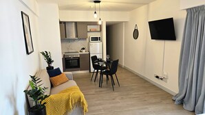 Um espaço compacto com cozinha compacta, área de refeições e televisão fixada na parede.