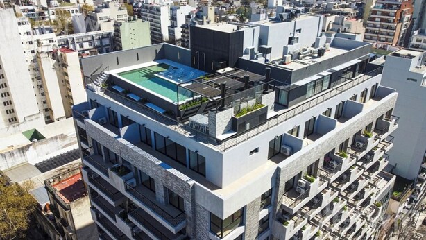Um edifício moderno de vários andares com piscina no terraço, amplas janelas e varandas.