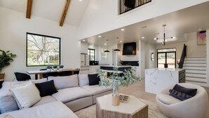 A spacious living area with a large sectional sofa, a round coffee table, and a modern kitchen in the background.